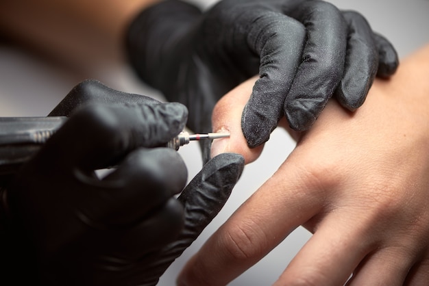 Manicurista maestro profesional trabajando en las uñas del cliente