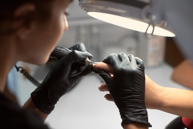 Manicurista maestro profesional trabajando en las uñas del cliente