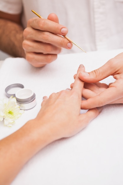 Manicurista pintando a los clientes uñas