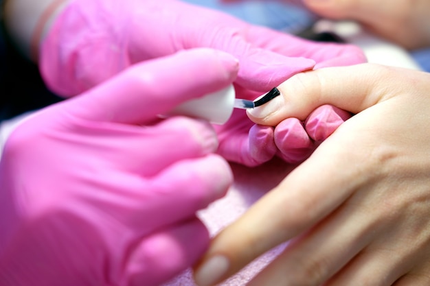 Foto manicurista pintando uñas con esmalte de uñas