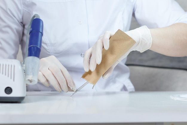 Manicurista profesional abre una bolsa de papel con herramientas de manicura estériles