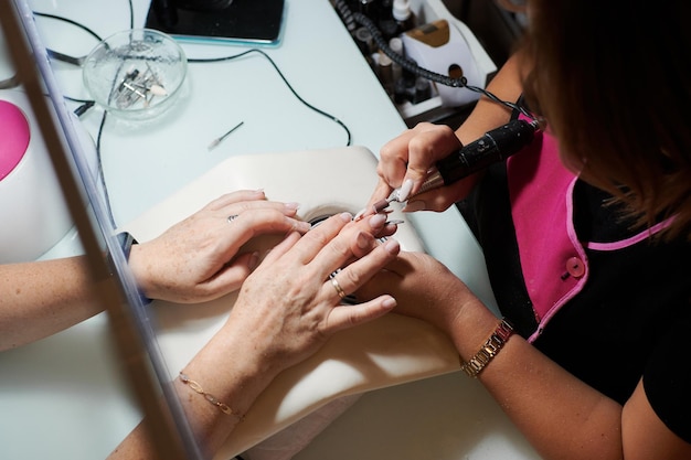 Manicurista profesional arregla y embellece las uñas de un cliente.