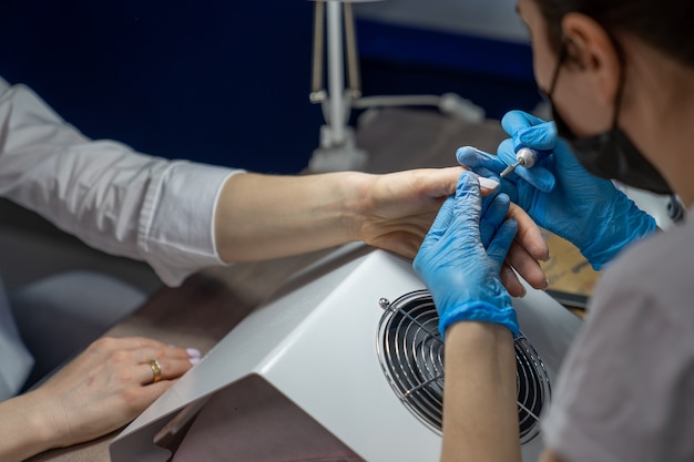 La manicurista quita el esmalte de uñas viejo con un cortador especial.