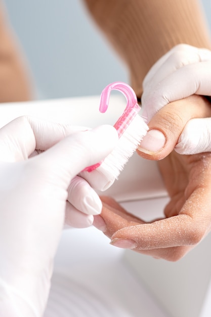 Manicurista quitando el polvo de las uñas.