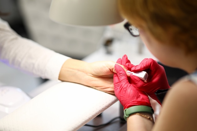 La manicurista en el salón realiza el recubrimiento de la placa de la uña con esmalte de gel una mujer