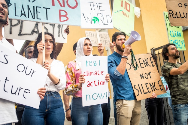 Manifestação pública na rua contra o aquecimento global e a poluição. Grupo de pessoas multiétnicas protestando contra mudanças climáticas e problemas plásticos nos oceanos