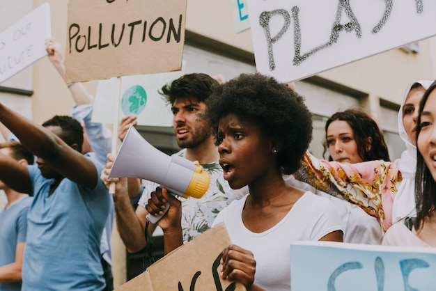 Manifestación pública en la calle contra el calentamiento global y la contaminación. Grupo de personas multiétnicas que protesta por el cambio climático y los problemas plásticos en los océanos.