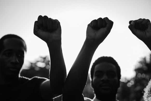 Foto manifestantes negros tomados de la mano contra el racismo centrarse en los puños edición en blanco y negro