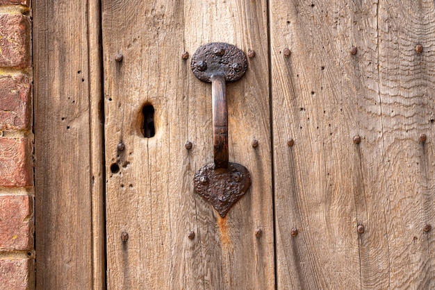 Manija de puerta oxidada en la vieja puerta desgastada con ojo de cerradura