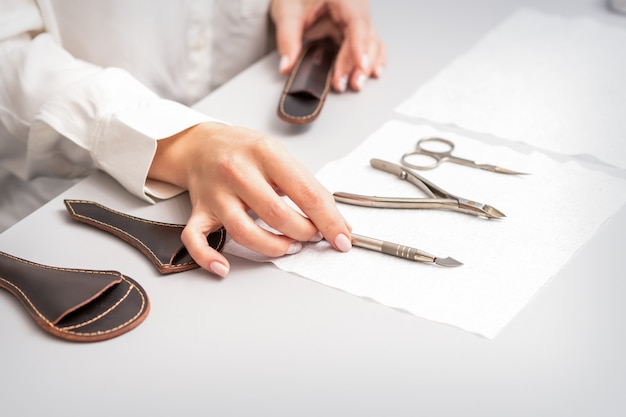 Maniküre-Meister legt Maniküre auf einem Handtuch am Tisch in einem Nagelstudio aus