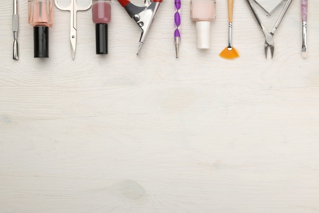 Maniküre. Nagellacke und verschiedenes Zubehör und Werkzeuge für die Maniküre auf einem weißen Holztisch. Ansicht von oben