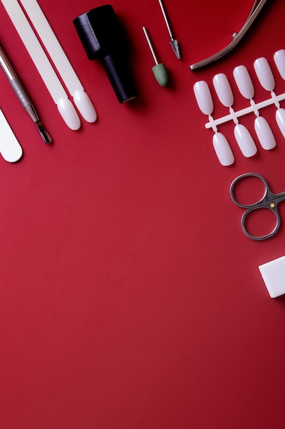 Manikürewerkzeuge und -tipps auf rotem Hintergrund mit Kopienraum. Gelpolierbeschichtungskonzept