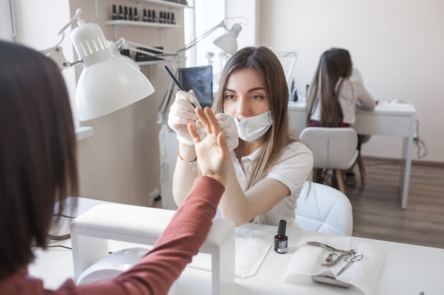 Manikürist macht eine Maniküre im Salon. Meister, der ihren Klienten betreut. Nagelpflege.