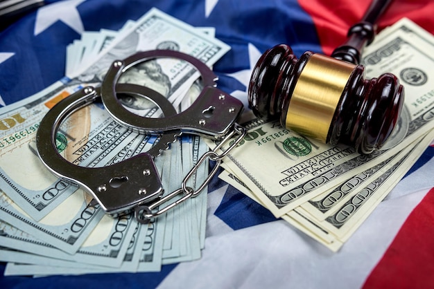 Manilhas de metal e o martelo de um juiz e notas de dólar estão em uma bandeira americana Conceito de crimes financeiros ou corrupção