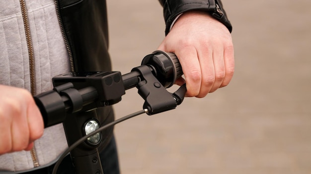 Manillar de scooter eléctrico y mano de hombre en la palanca durante la verificación de frenos antes de conducir y practicar la conducción