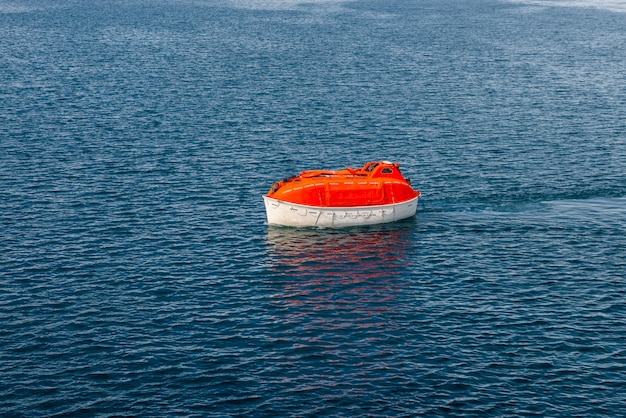 Foto maniobra naranja bote salvavidas en el agua en las aguas del ártico, svalbard. abandonar el simulacro de barco. entrenamiento en bote salvavidas. hombre al agua taladro.