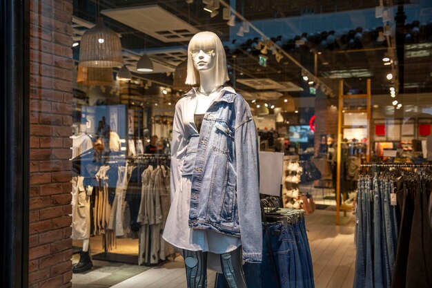 Un maniquí femenino en una chaqueta de mezclilla en una vitrina de una tienda de ropa juvenil de moda Estilo y belleza Primer plano