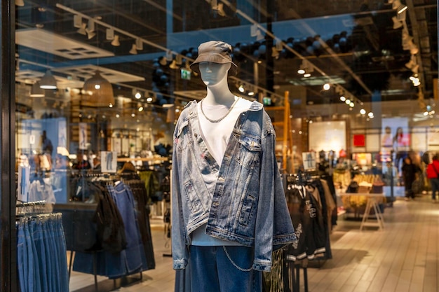 Un maniquí masculino en una chaqueta de mezclilla en una vitrina de una tienda de ropa juvenil de moda Estilo y belleza Primer plano