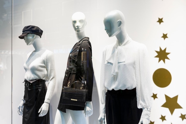 Maniquíes femeninos en un escaparate decorado festivamente de una elegante tienda de ropa.