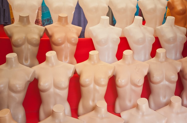 Maniquíes de plástico desnudos blancos sobre fondo rojo.