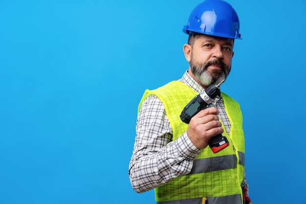 Manitas constructor en casco azul sosteniendo un destornillador contra el fondo azul.