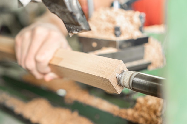 Manitas de cultivo que opera la máquina de torneado de madera en el trabajo