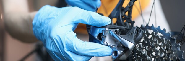 Manitas en guantes de goma reparación de bicicletas en primer plano del taller