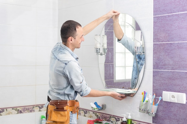 Foto manitas instalando un espejo en el baño.