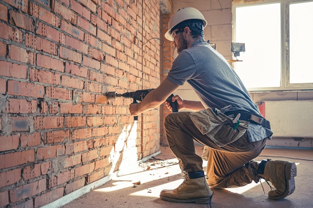 Manitas en un sitio de construcción en el proceso de perforación de una pared con un perforador.