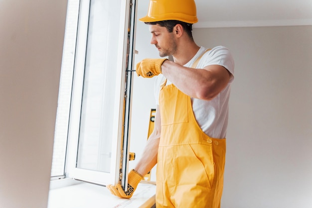 Manitas en uniforme amarillo instala nueva ventana Concepción de renovación de la casa