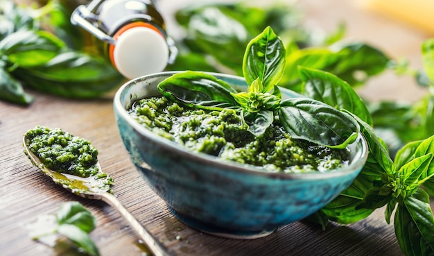 Manjericão fresco deixa pesto na mesa de madeira.