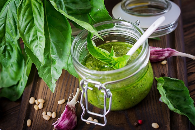 Foto manjericão fresco do molho caseiro do pesto, pinhões e alho na superfície de madeira. comida italiana.