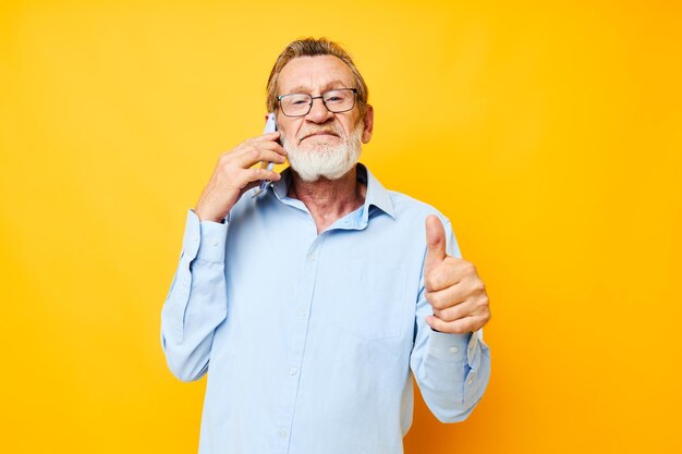 Mann alter Mann mit Telefon posiert auf gelbem Hintergrund