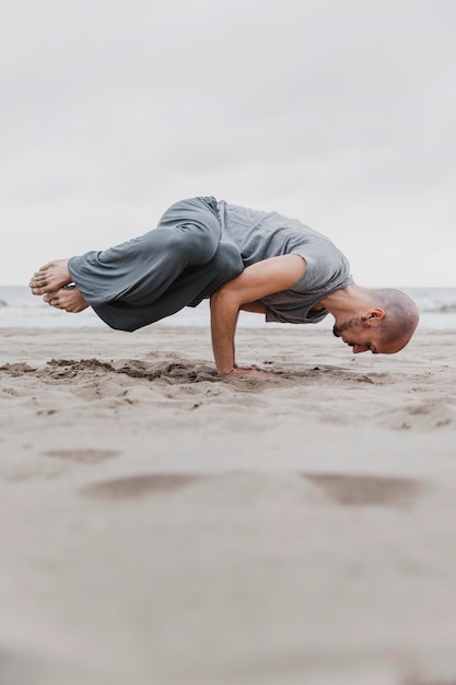 Mann am Strand, der Yoga-Positionen praktiziert