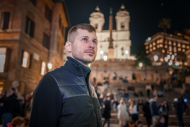 Mann an der spanischen Stufe in Rom denkt an die beleuchtete Kirche