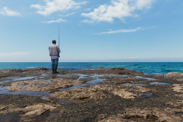 Mann an Land, der auf einem Meer fischt