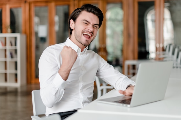 Mann an seinem Arbeitsplatz mit Laptop im Büro