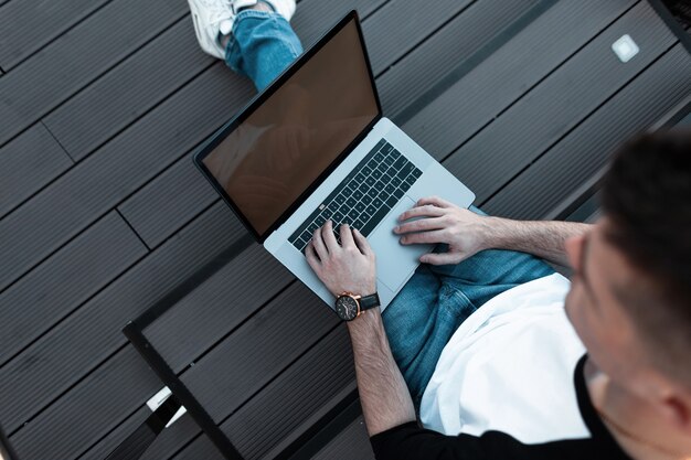 Mann arbeitet am Laptop auf der Straße