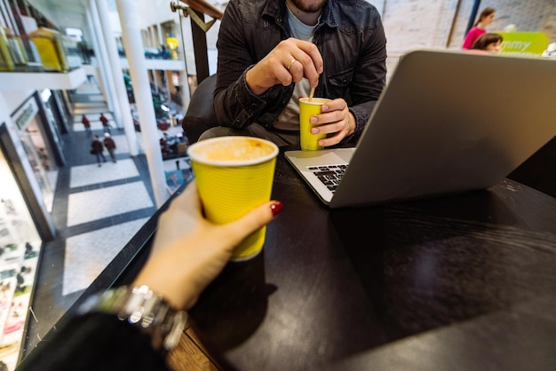 Mann arbeitet am Laptop im Einkaufszentrum. paar sitzen im café trinkt kaffee. Platz kopieren