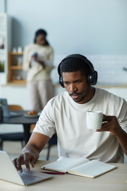 Mann arbeitet am Laptop und trinkt Kaffee