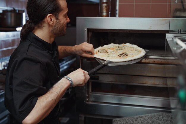 Mann arbeitet in der Küche eines Restaurants und bereitet traditionelle Pizzen vor