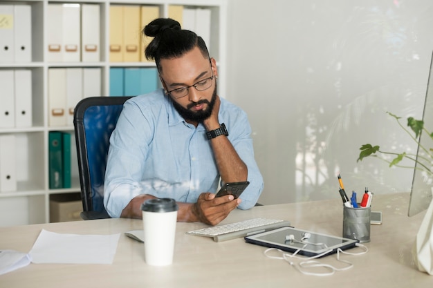 Mann arbeitet, während er sein Telefon überprüft