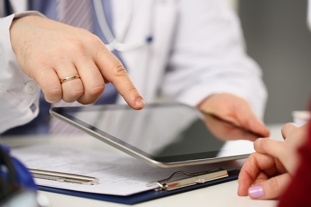 Mann Arzt konsultieren Patientin Punkt mit Finger auf Tablet-Gerät
