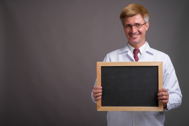 Mann Arzt mit blonden Haaren gegen graue Wand