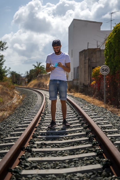 Mann auf Bahngleis mit Maske, weißem T-Shirt und Jeans