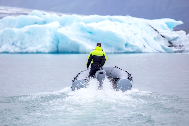 Mann auf einem schnellen Motorboot, das auf einer Gletscherlagune in Island segelt