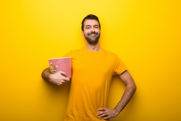 Mann auf getrennter vibrierender gelber Farbe Popcorn essend