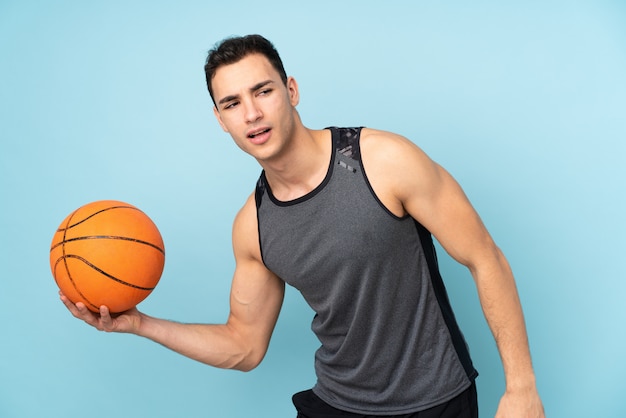 Mann auf isolierter blauer Wand, die Basketball spielt