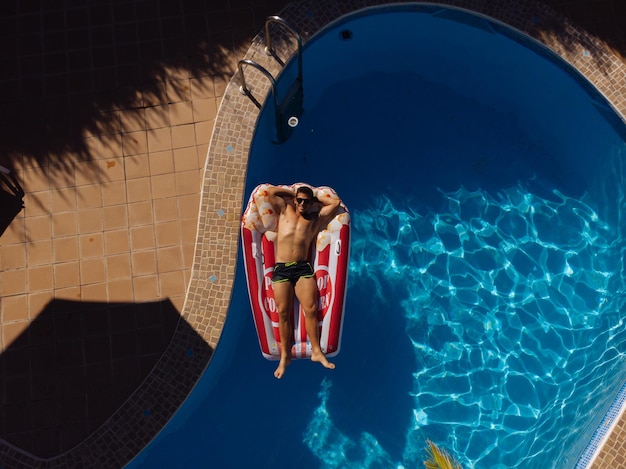 Mann auf Strandmatte im Swimmingpool eines Villenhauses