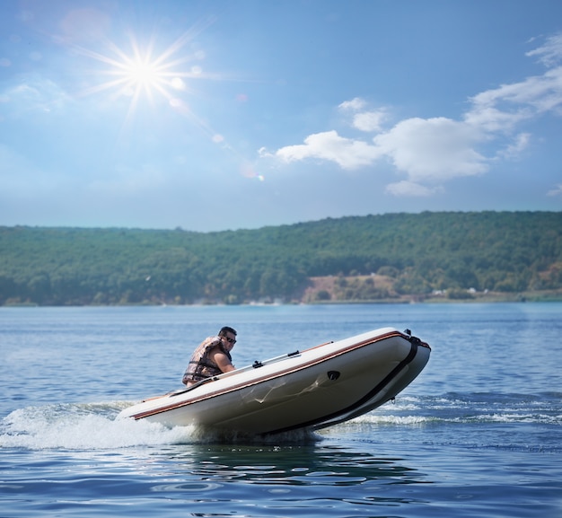 Mann auf weißem aufblasbarem Motorboot